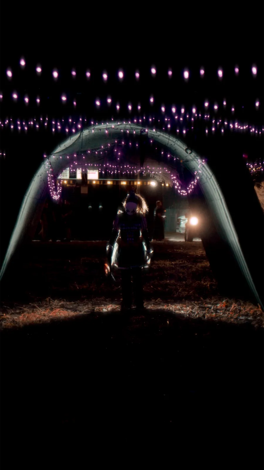 A costumed scare actor lit from below at the entrance to the night trail
