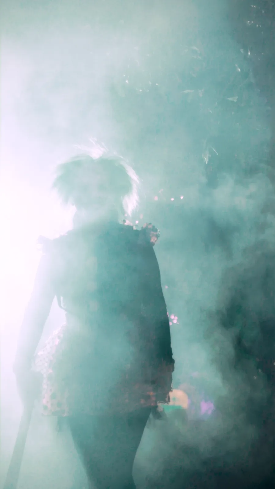 A figure silhouetted in fog beside the glow trail