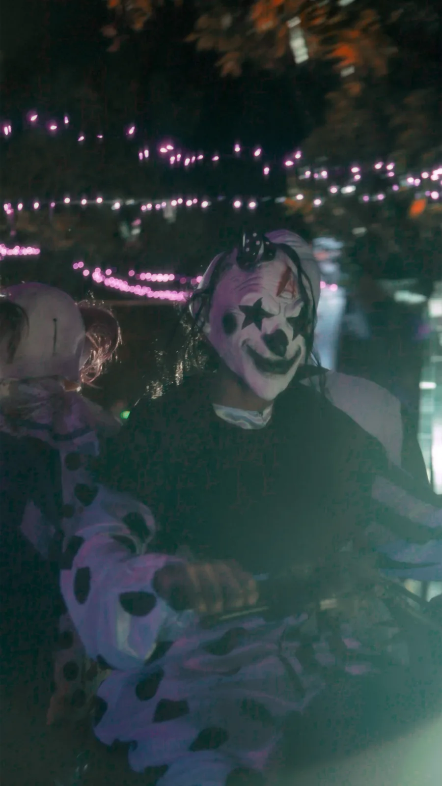 Riders in costume under string lights at the check-in area before a glow tour